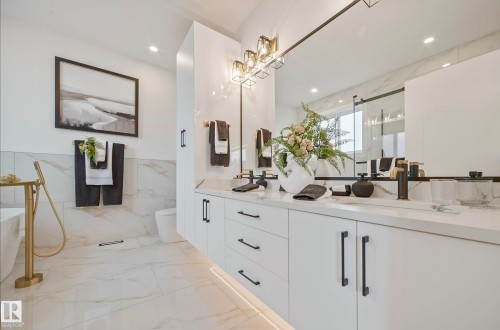 Spacious bathroom featuring a double vanity with white cabinetry and black hardware, stone countertops, and a full-width mirror - 16607 8 Street, Edmonton, AB 