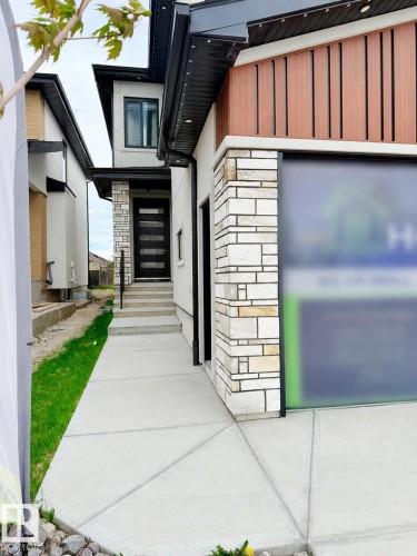 Contemporary exterior showcasing a multi-textured facade with stone accents and wood-finish paneling - 16607 8 Street, Edmonton, AB 