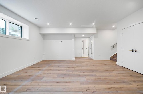 Spacious room featuring wood-finish flooring, recessed lighting, and white walls - 16607 8 Street, Edmonton, AB 