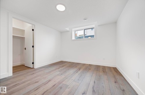 Bright room featuring wood-finish flooring, white walls, and a recessed ceiling light - 16607 8 Street, Edmonton, AB 