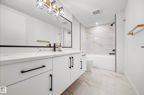 Double vanity featuring white cabinetry with matte black hardware, a light-toned countertop, and a large wall-mounted mirror - 16607 8 Street, Edmonton, AB 