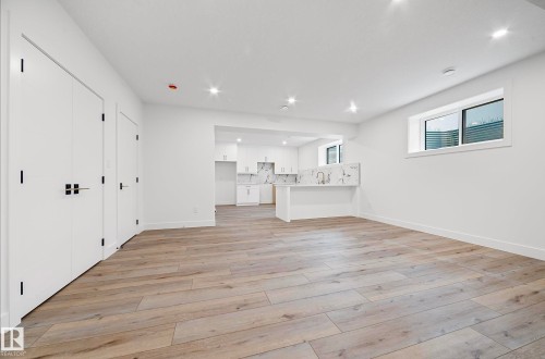 Expansive open-concept living area featuring wood-finish flooring, recessed lighting, and a neutral color palette - 16607 8 Street, Edmonton, AB 