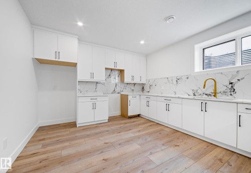 Kitchenette featuring white cabinetry, a gold-tone faucet, a white undermount sink, and light wood-finish flooring - 16607 8 Street, Edmonton, AB 