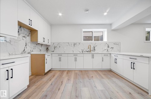 Modern kitchen featuring white cabinetry, a marble-patterned backsplash, white countertops, wood-finish flooring, and recessed lighting - 16607 8 Street, Edmonton, AB 