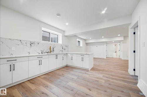 Spacious open-concept area featuring a white cabinetry run with a white countertop and a marbled-patterned backsplash - 16607 8 Street, Edmonton, AB 