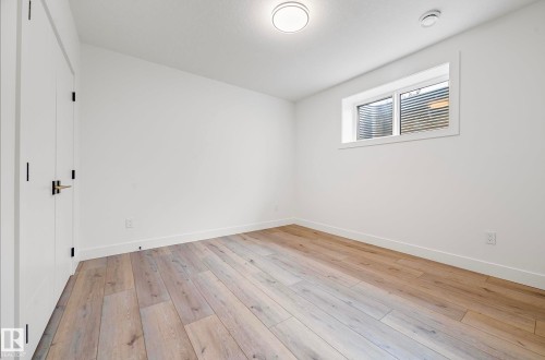 Bright interior space featuring light wood-finish flooring, white walls, and a window with horizontal blinds - 16607 8 Street, Edmonton, AB 