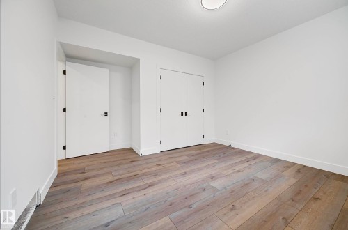 Room featuring wide plank wood-finish flooring, white baseboards, and a neutral wall color - 16607 8 Street, Edmonton, AB 