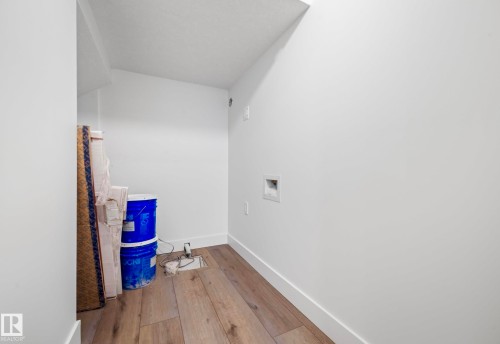 Dedicated laundry area featuring wood-finish flooring, white walls, and a built-in dryer vent - 16607 8 Street, Edmonton, AB 