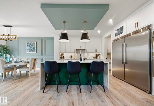 Open-concept kitchen featuring a large central island with a contrasting green base, white countertops, and two pendant lights - 16607 8 Street, Edmonton, AB 