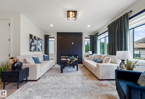 Spacious living area featuring a contemporary fireplace with a dark, marbled surround, recessed lighting, and large windows with privacy blinds - 16607 8 Street, Edmonton, AB 