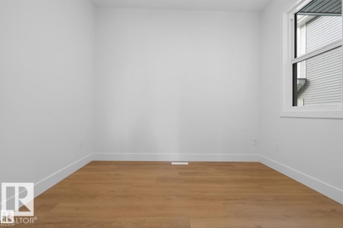 Bright interior space featuring wood-finish flooring, white walls, white trim, and a white-framed window - 19 Rosa Crescent, St. Albert, AB 