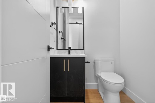 Contemporary bathroom featuring a black vanity with gold-tone pulls, a white countertop, and a rectangular mirror with black trim - 19 Rosa Crescent, St. Albert, AB 