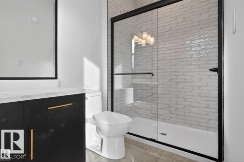 Contemporary bathroom featuring a spacious glass-enclosed shower with subway tile surround, a sleek black vanity with gold hardware, a white countertop, and large format floor tiling - 19 Rosa Crescent, St. Albert, AB 