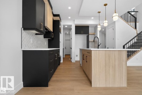 Modern kitchen featuring two-tone cabinetry with black lower and light wood-finish upper cabinets - 19 Rosa Crescent, St. Albert, AB 