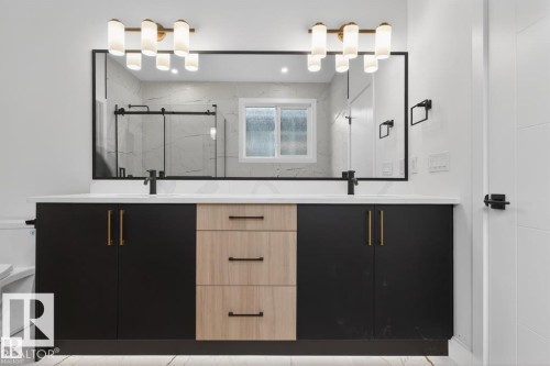 Dual vanity with a white countertop and contrasting black and light wood-finish cabinetry - 19 Rosa Crescent, St. Albert, AB 