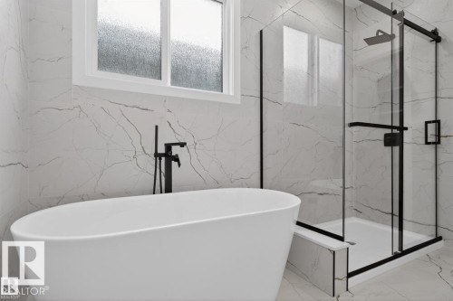 Modern bathroom featuring a freestanding soaking tub with a matte black floor-mounted faucet, a spacious glass-enclosed shower with black framing and a rain showerhead, and large format marble-look wall and floor tiles - 19 Rosa Crescent, St. Albert, AB 