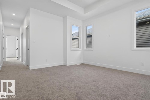 Spacious room featuring neutral carpet flooring, white walls, and a tray ceiling - 19 Rosa Crescent, St. Albert, AB 