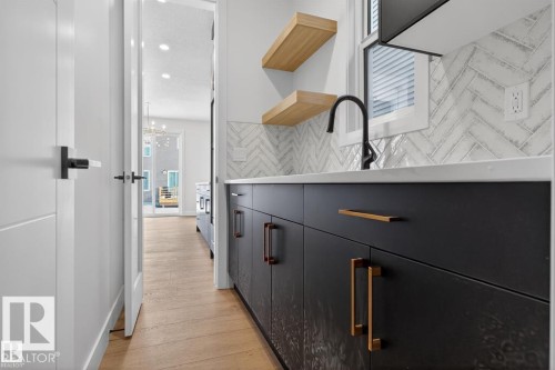 Modern kitchen area with black cabinetry, brass hardware, and a white countertop - 19 Rosa Crescent, St. Albert, AB 