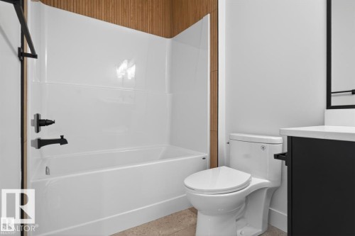 Bathroom featuring a white tub and shower surround, matte black fixtures, a white toilet, and a dark-toned vanity with a white countertop - 19 Rosa Crescent, St. Albert, AB 