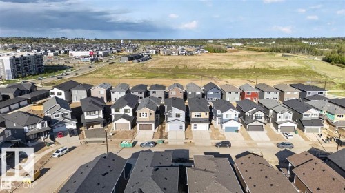 Aerial perspective of a developing residential neighborhood featuring various modern homes with attached garages, paved driveways, and dark shingle roofs - 19 Rosa Crescent, St. Albert, AB 