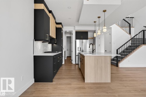 Modern kitchen featuring wood-finish flooring and a central island with integrated sink - 19 Rosa Crescent, St. Albert, AB 