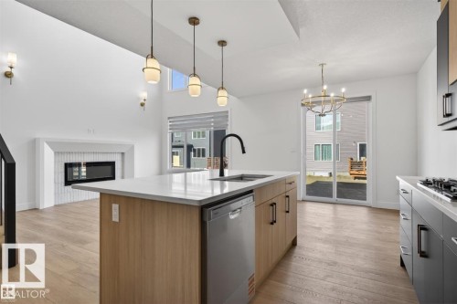 Modern kitchen island with a light wood-finish base, white countertop, and integrated dishwasher - 19 Rosa Crescent, St. Albert, AB 