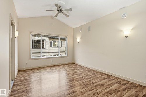 Vaulted ceiling room featuring wood-finish flooring, a large multi-pane window, and a ceiling fan - 50 2565 Hanna Crescent, Edmonton, AB 
