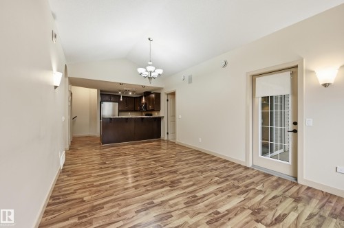 Open-concept living space featuring wood-finish flooring, vaulted ceilings, and a glass-paneled door - 50 2565 Hanna Crescent, Edmonton, AB 