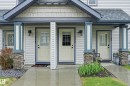 Exterior entryways featuring light-colored siding, a dark gray roof, and stone veneer accents on porch columns - 50 2565 Hanna Crescent, Edmonton, AB 
