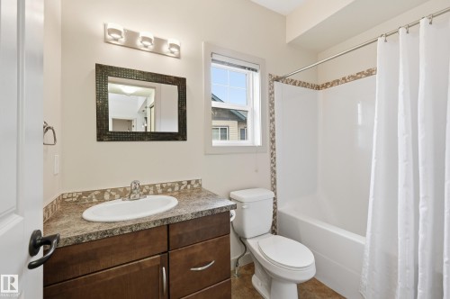 Bathroom featuring a dark wood-finish vanity with an integrated sink, a tiled countertop, and a vanity mirror - 50 2565 Hanna Crescent, Edmonton, AB 