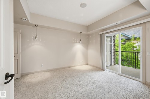 Carpeted interior space featuring a sliding glass door opening to a private balcony with black metal railing - 50 2565 Hanna Crescent, Edmonton, AB 