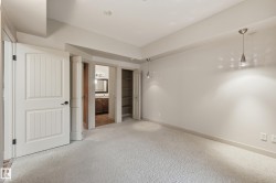 Carpeted interior space featuring light-colored walls and two contemporary pendant light fixtures - 