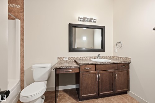 Vanity with integrated sink, dark wood-finish cabinetry, and stone-look countertop - 50 2565 Hanna Crescent, Edmonton, AB 