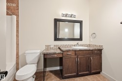 Vanity with integrated sink, dark wood-finish cabinetry, and stone-look countertop - 