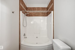 Bathtub and shower combination featuring a white surround and a curved basin - 