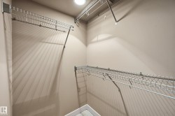 Walk-in closet featuring light-colored walls, recessed ceiling lighting, and multiple levels of wire shelving for storage - 