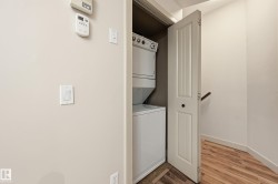 Dedicated laundry closet featuring a stacked white washer and dryer unit, wood-finish flooring, and a white paneled door - 