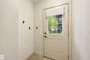 Entryway featuring a paneled door with a grid window, an opaque roll-up shade, and three wall-mounted hooks - 50 2565 Hanna Crescent, Edmonton, AB 