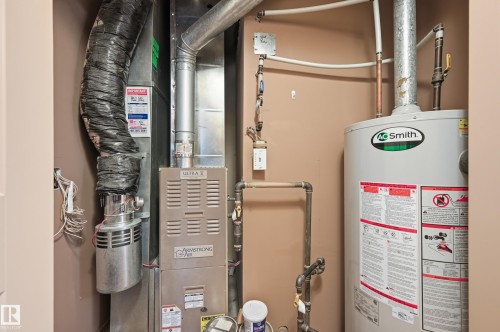 Dedicated utility space featuring a water heater and furnace with exposed ductwork - 50 2565 Hanna Crescent, Edmonton, AB 