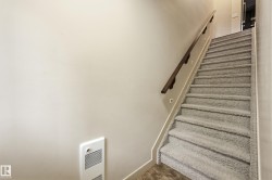 Carpeted staircase featuring a dark wood handrail, recessed wall lighting, and neutral wall paint - 