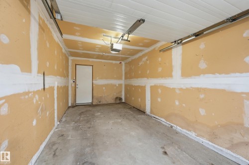 Garage interior featuring a concrete floor, painted drywall, and a white access door - 50 2565 Hanna Crescent, Edmonton, AB 