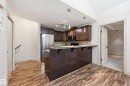 Kitchen featuring dark wood-finish cabinetry, stainless steel appliances, and a breakfast bar with stone-finish countertops - 50 2565 Hanna Crescent, Edmonton, AB 