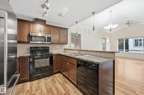 Kitchen with wood-finish flooring and dark wood cabinetry - 50 2565 Hanna Crescent, Edmonton, AB 