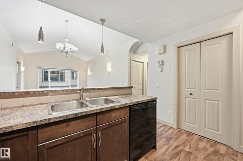 Kitchen featuring a double basin stainless steel sink, dark wood-finish cabinetry, and a black dishwasher - 50 2565 Hanna Crescent, Edmonton, AB 