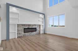 Living area featuring a stone-clad fireplace with an electric insert, built-in shelving with recessed lighting, shiplap detailing, and wood-finish flooring - 