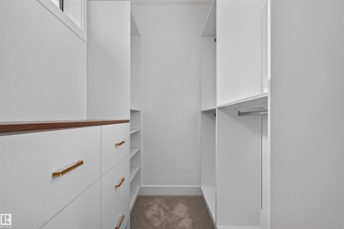 Built-in closet system featuring white cabinetry, wood-finish countertop, gold-tone hardware, integrated shelving, and hanging rods - 84 Rosa Crescent, St. Albert, AB - Indoor