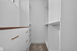 Built-in closet system featuring white cabinetry, wood-finish countertop, gold-tone hardware, integrated shelving, and hanging rods - 