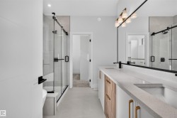 Modern bathroom with a dual vanity featuring wood-finish and white cabinetry, a stone-finish countertop, and integrated sinks - 