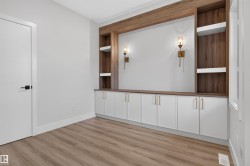 Built-in media center featuring a wood-finish frame, integrated shelving, and white base cabinetry with gold-tone hardware - 