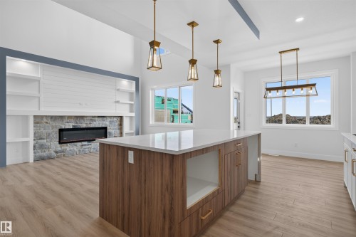 Spacious kitchen island with wood-finish cabinetry, white quartz countertop, and integrated storage - 84 Rosa Crescent, St. Albert, AB - Indoor Photo Showing Other Room With Fireplace